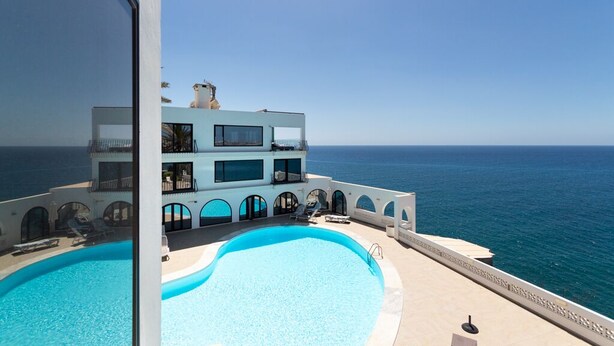 A modern two-story building with a pool and ocean views.