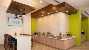 A modern kitchen area with a central island, wooden chairs, and a bright green accent wall. - Fairfield by Marriott® Inn & Suites San Luis Potosi (San Luis Potosi)