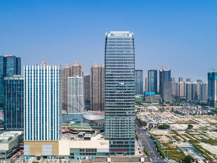 Un edificio de gran altura con fachada de vidrio moderna, rodeado de otros edificios altos en un paisaje urbano.
