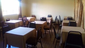 A conference room with multiple tables and chairs, a ceiling fan, and a window with curtains.