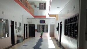 A corridor with a patterned floor, a potted plant, and a staircase leading to an upper level.