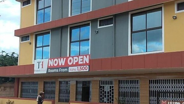 A multi-story building with a sign indicating it is now open, featuring rooms starting from Kshs. 1,500.