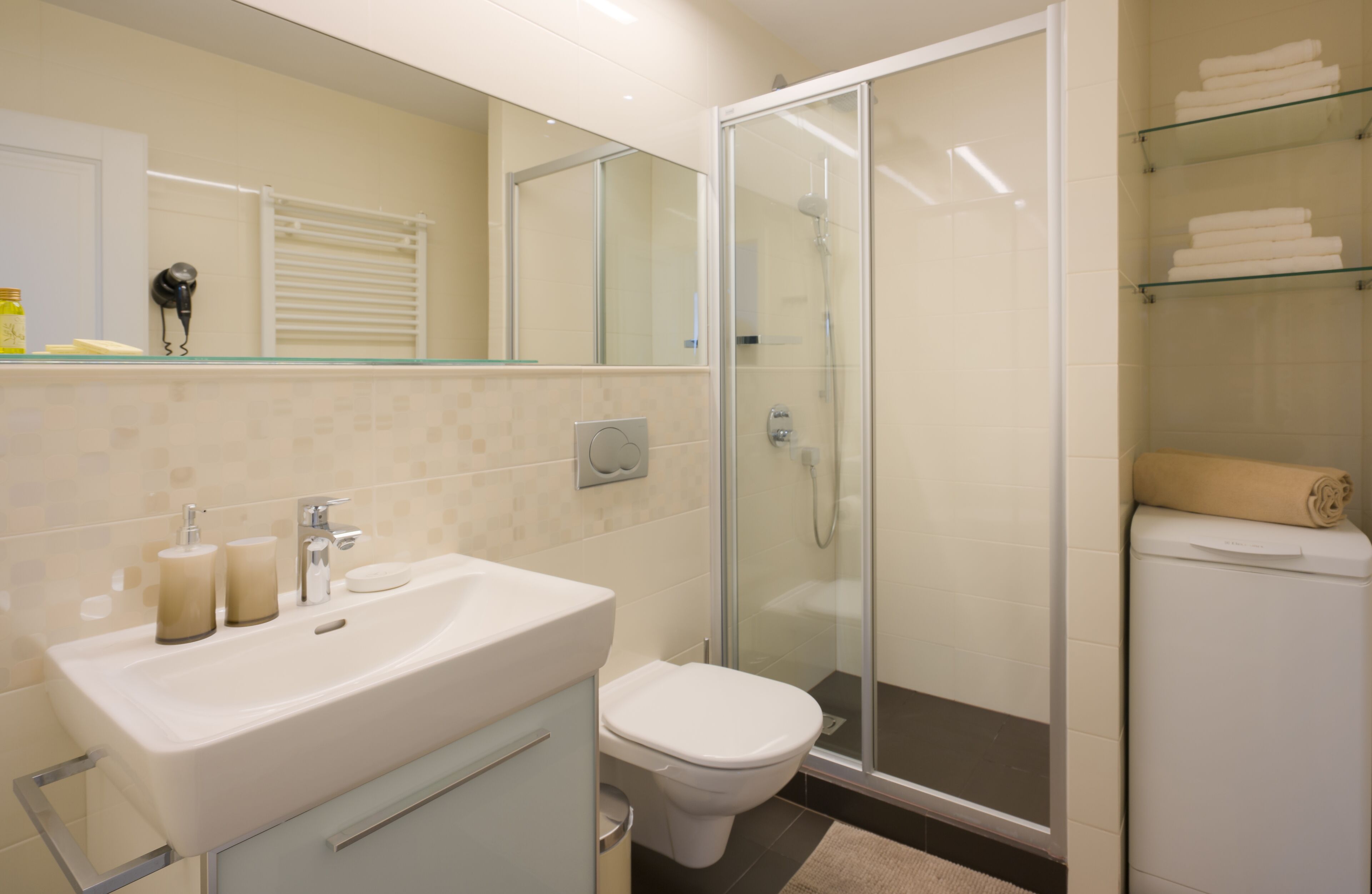 A modern bathroom with a glass-enclosed shower, a white sink, and a toilet.
