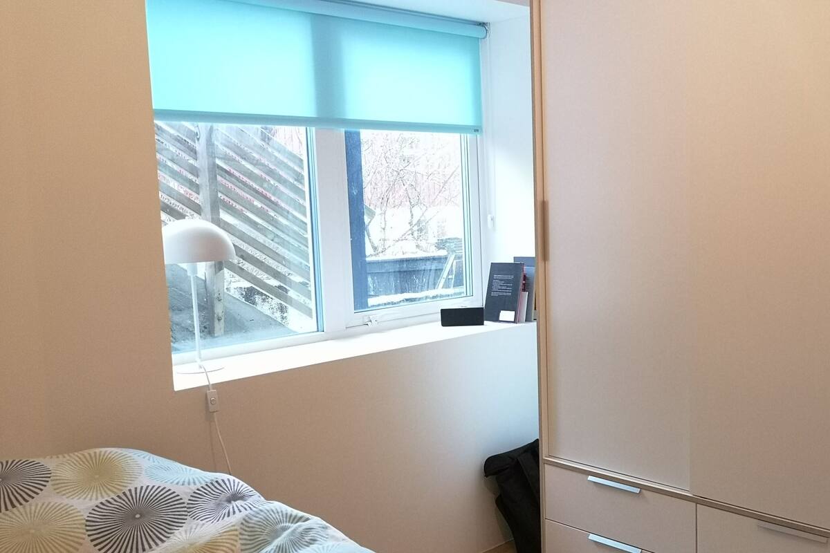 Une chambre à coucher avec un lit, une fenêtre, une armoire et un bureau avec une lampe.