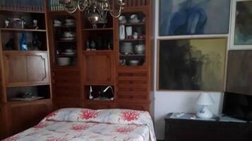 Una stanza con un letto, un lampadario, una libreria e un quadro appeso al muro.