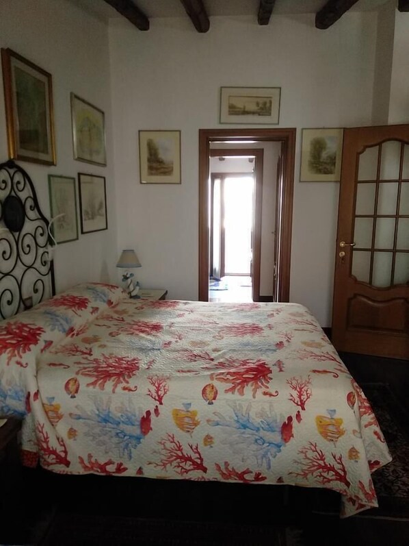 Un dormitorio con cama, una puerta y cuadros en las paredes.