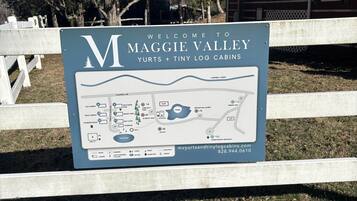 A welcome sign for Maggie Valley Yurts + Tiny Log Cabins with a map of the campground.