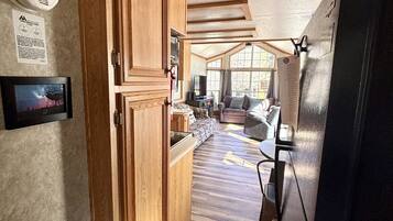 A kitchen with wooden cabinets, a black refrigerator, and a window with curtains.