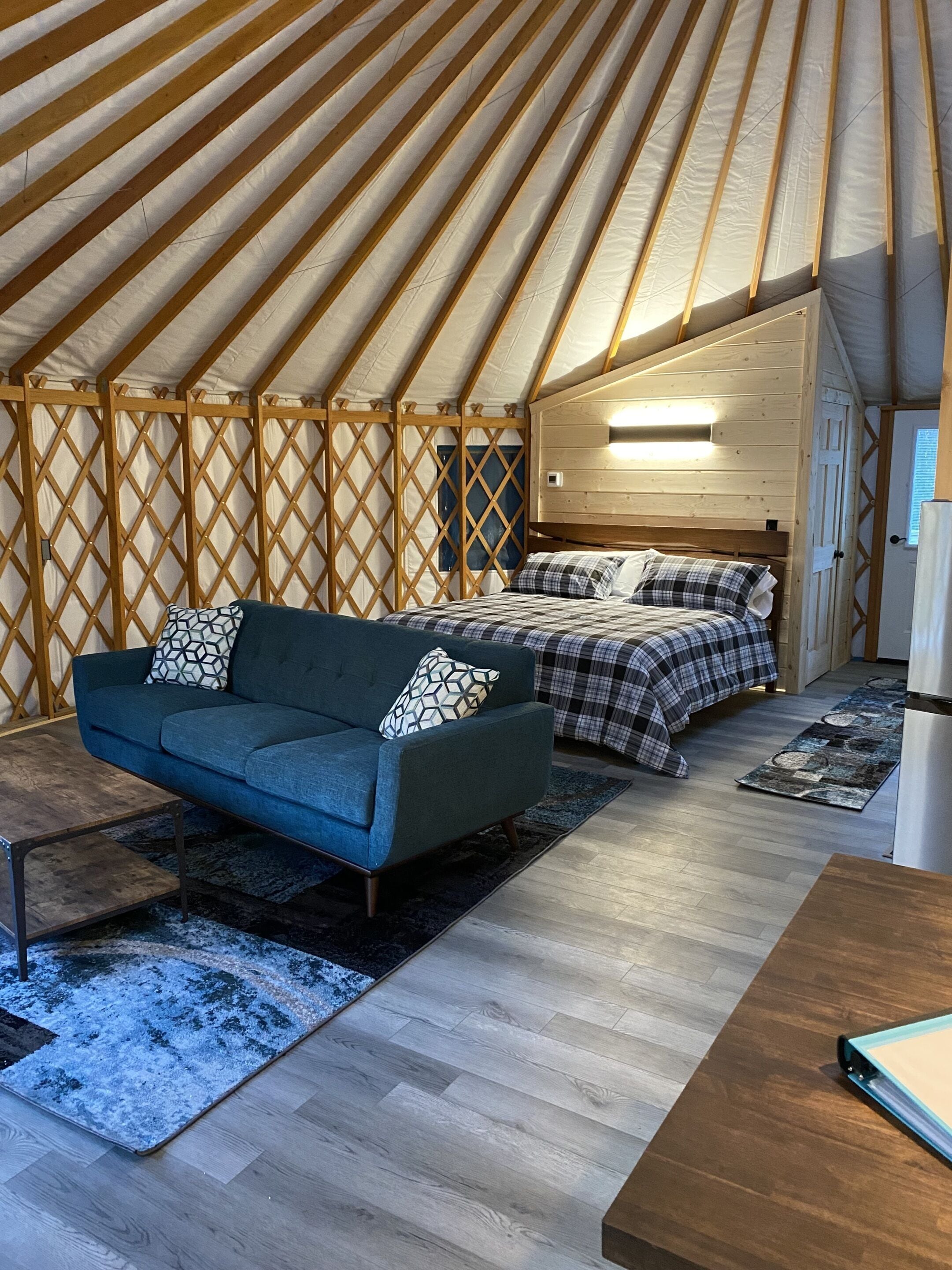Ein gemütliches Zeltinnenleben mit einer Couch, einem Bett und einem Holzboden.