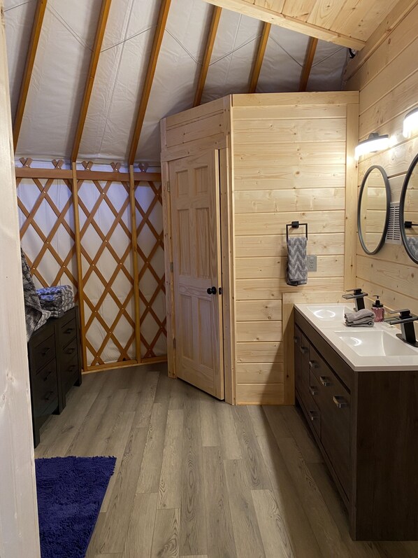 A compact, wooden interior with a built-in wardrobe, a vanity with a mirror, and a blue rug on the floor. - Maggie Valley Cabin Rentals (Maggie Valley)
