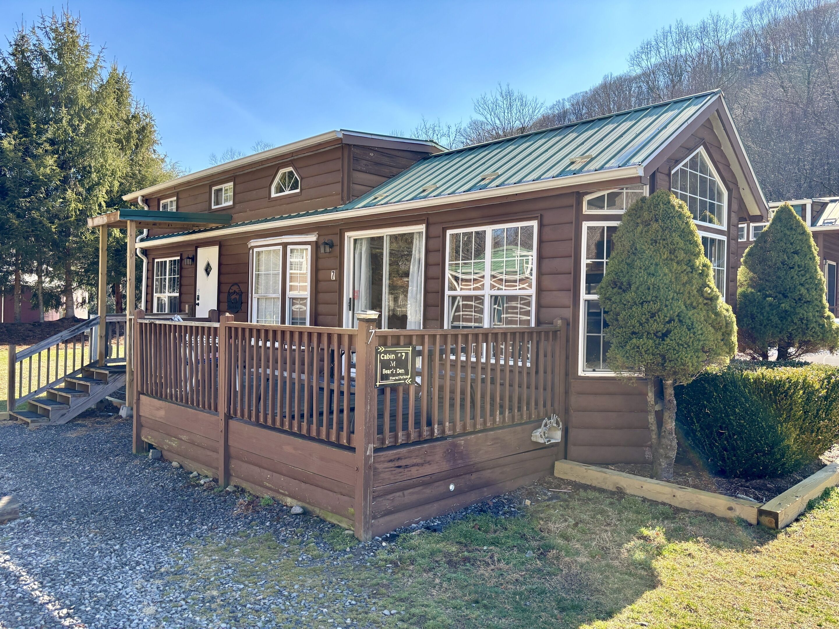 A cabin with a wooden exterior, a porch, and a metal roof.