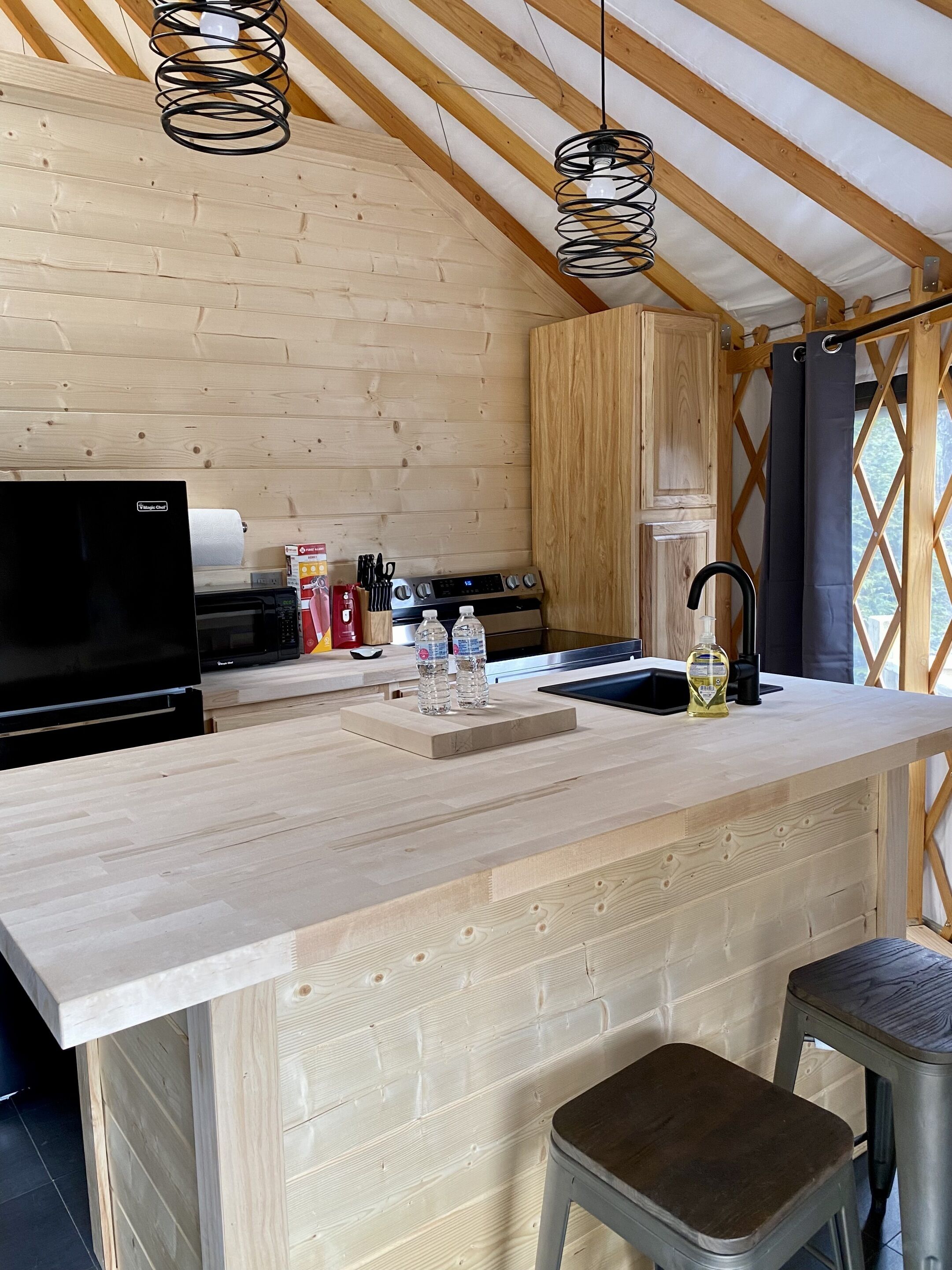 A modern kitchen with wooden beams, a built-in stove, and a bar area with stools.
