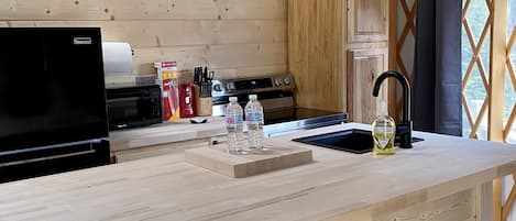 A modern kitchen with wooden beams, a built-in stove, and a bar area with stools.