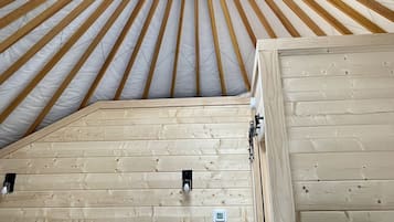 A circular wooden ceiling structure with a central fan, wooden beams, and a skylight.