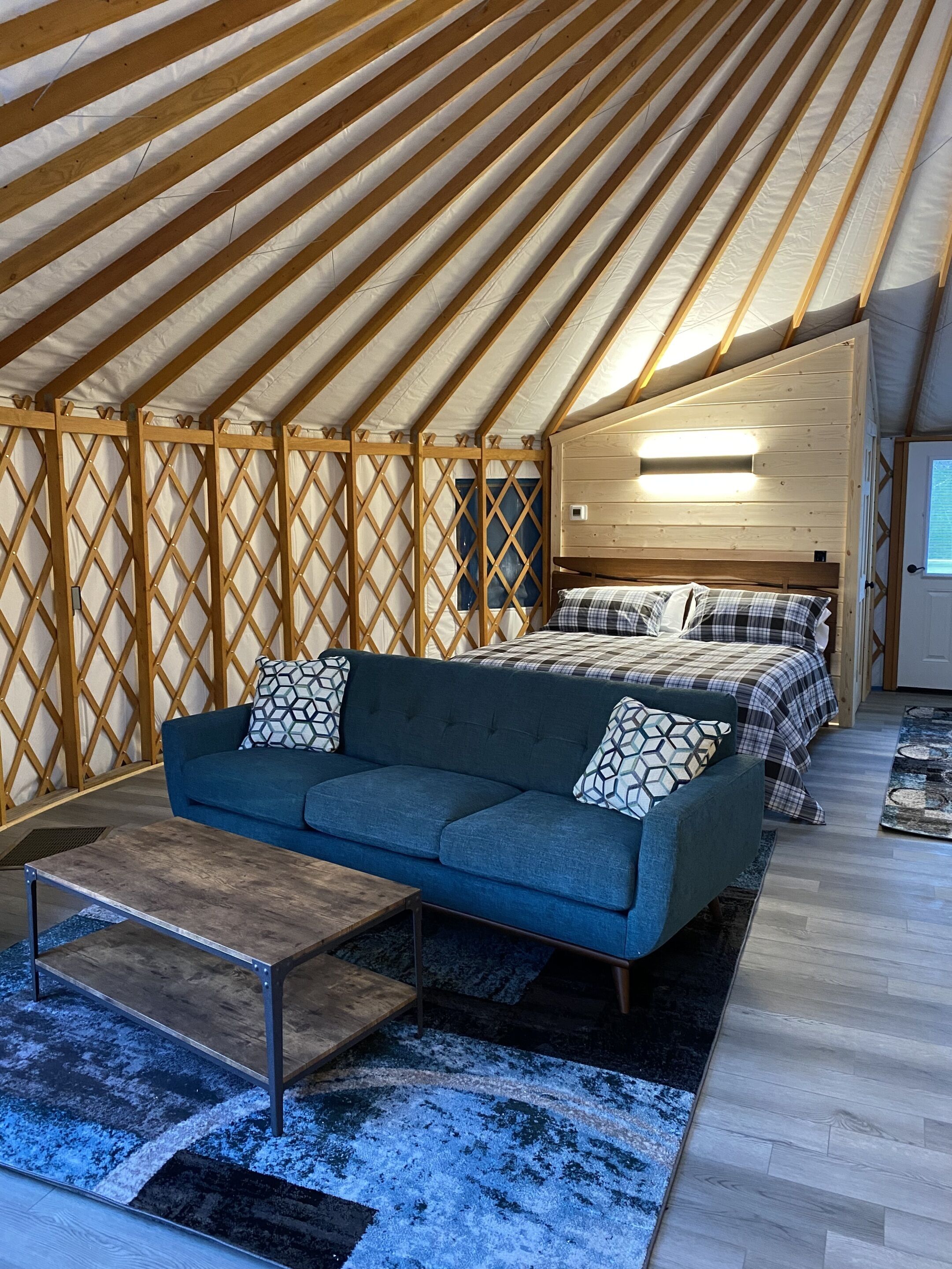 Een gezellige, goed verlichte tentkamer met een bed, een slaapbank en een klein tafeltje.