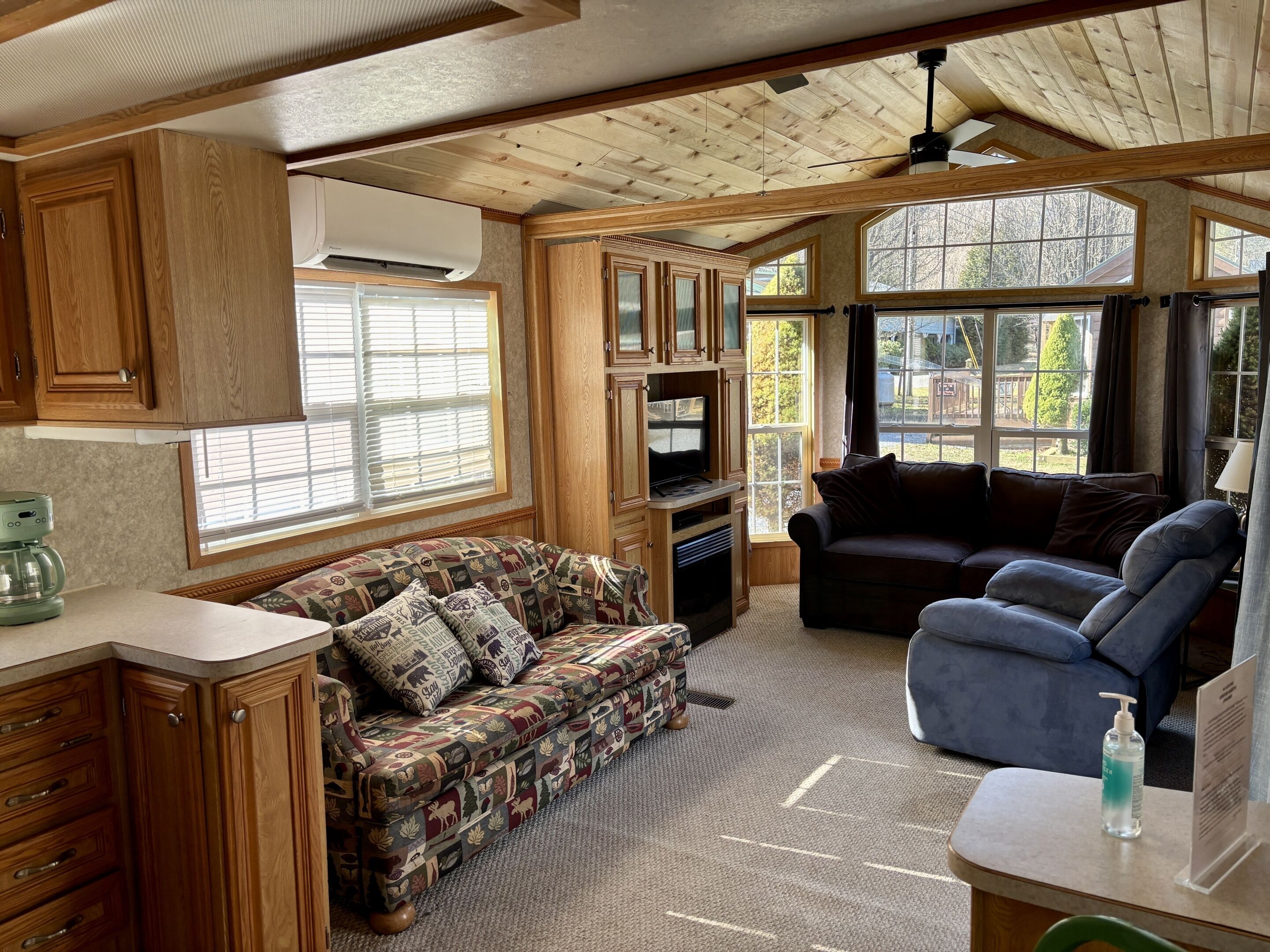 Interior compacto de una autocaravana con kitchenette, dos zonas de estar y amplias ventanas con vistas al exterior.