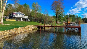 A lakeside property with a house, dock, and clear water. - Lakeshore Cottage- Family and Pet Friendly, Lakefront, Fireplace, and Gameroom (Fort Ann)
