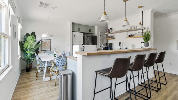 A modern kitchen with a central island, bar stools, and pendant lighting. - Only 5 blocks to King! | Rose and Petunia Suites (Charleston)