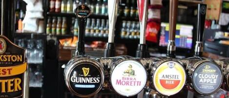 A bar with multiple beer taps including brands like Guinness, Birra Moretti, Amstel, and Cloudy Apple.