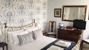 Un dormitorio con cama, cómoda, silla, televisor y espejo.