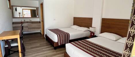 A hotel room with two beds, a desk, and a kitchenette.