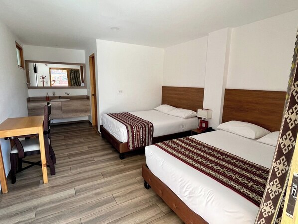 Una habitación de hotel con dos camas, un escritorio y una kitchenette.