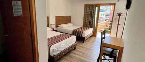 Une chambre d’hôtel avec deux lits, un bureau en bois et une télévision.