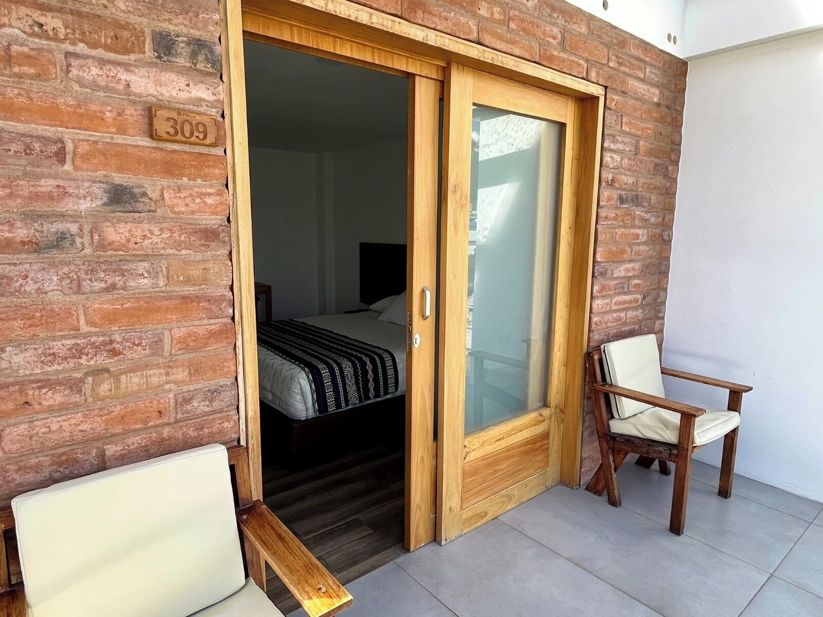 Una habitación con una cama, un banco de madera y una silla.