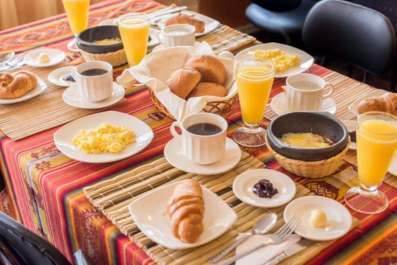 Taula de petit esmorzar amb croissants, ous barrejats i suc d'aranja.