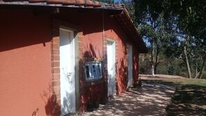 A red brick building with two white doors, a window, and a small outdoor area with a concrete path and a bottle. - Farm near São Paulo (São Roque)