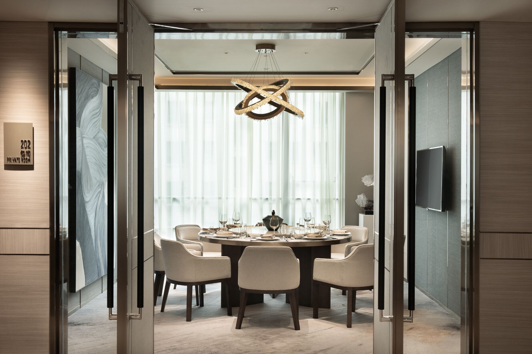 Un espace repas moderne avec une table ronde, six chaises et un lustre.