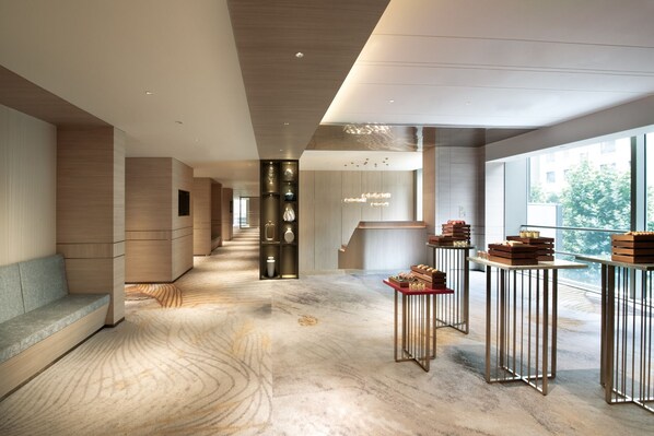 Un moderno vestíbulo de hotel con piso de mármol, una escalera central y una zona de estar.