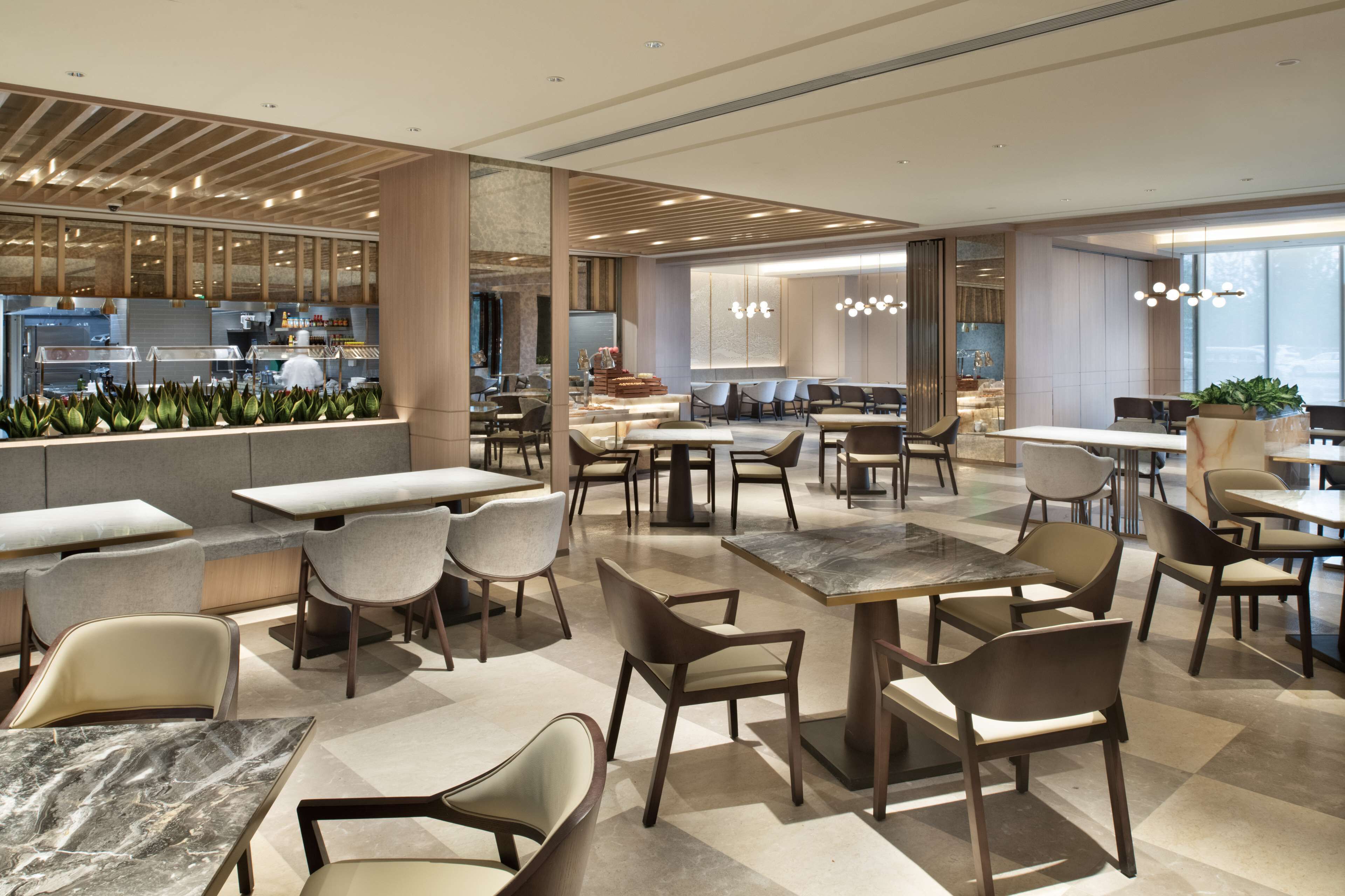 A modern restaurant with a variety of seating options including tables and chairs, a kitchen area, and a bar.