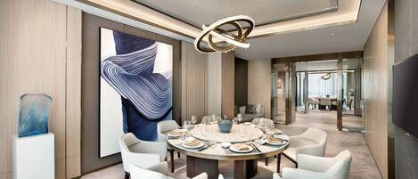 A modern dining room with a round table, white chairs, and a large abstract painting on the wall.