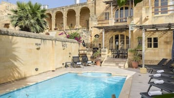 A swimming pool with lounge chairs and a patio area with tables and chairs.
