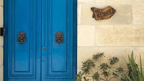 Una porta blu con maniglie a forma di testa di leone e una targa di legno con su scritto 