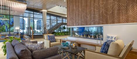 A modern lobby with a wooden ceiling, a large aquarium, comfortable seating, and a staircase.