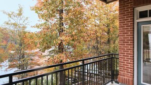 Ein Balkon mit einer Backsteinmauer und Blick auf Bäume sowie ein Gewässer.