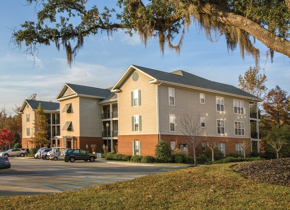A multi-story hotel with a brick facade, balconies, and a parking lot. - Wyndham Vacation Resorts Lake Marion (Santee)