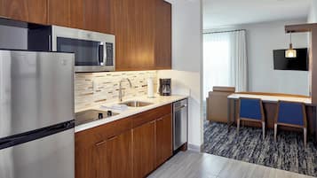 A modern kitchen with wooden cabinets, stainless steel appliances, and a dining area with two chairs and a table.