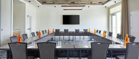 Una sala conferenze con un lungo tavolo, sedie, un televisore a schermo piatto e una moquette fantasia.