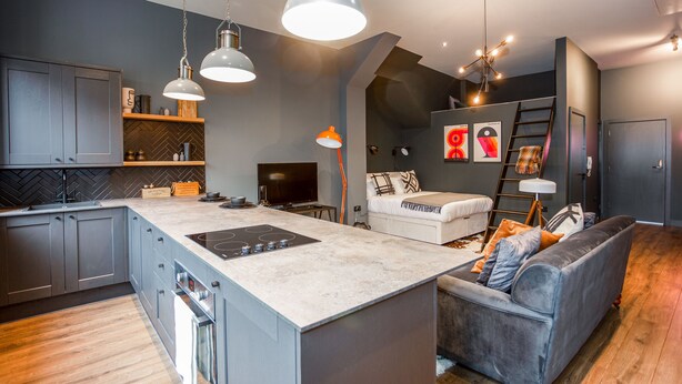 Una cocina moderna con gabinetes grises, una isla central e iluminación colgante.