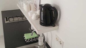 Una cocina moderna con encimera negra, pileta de acero inoxidable y hervidor.