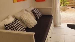 Una habitación con sofá cama, dos cuadros y vistas a un jardín.