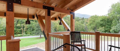 A wooden deck with a railing, a bench, and a rocking chair.