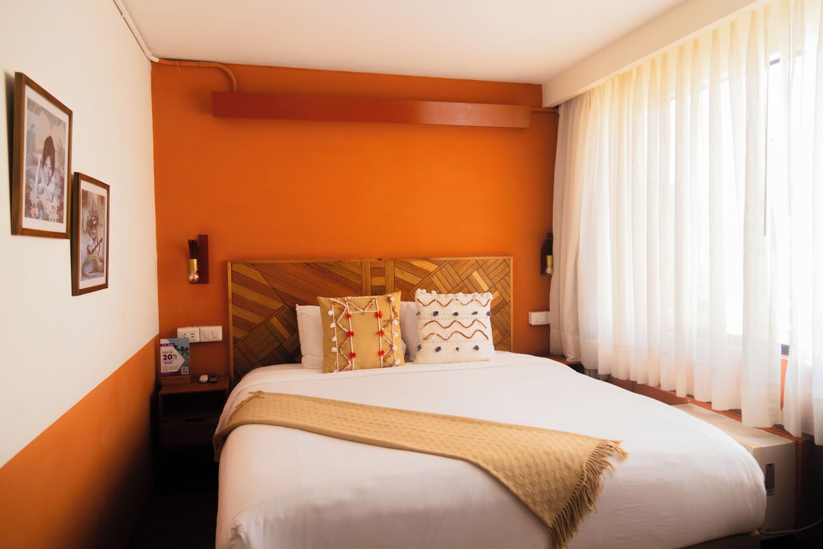 A hotel room with a large bed, orange walls, and a wooden headboard.