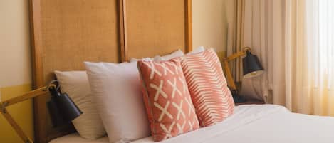 A neatly made bed with a wooden headboard, two bedside lamps, and patterned pillows.