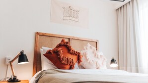 A neatly made bed with a wooden headboard, two bedside lamps, and a wall-mounted artwork. - qema Lima (Lima)