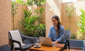 A person seated at a table with a laptop, a cup, and a notebook. - qema Lima (Lima)