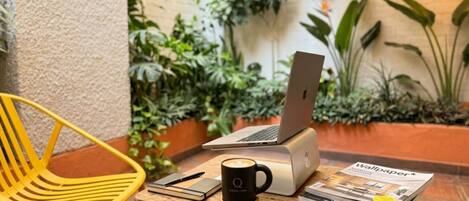 Una mesa de madera con una computadora portátil, una taza de café, un cuaderno y una revista.